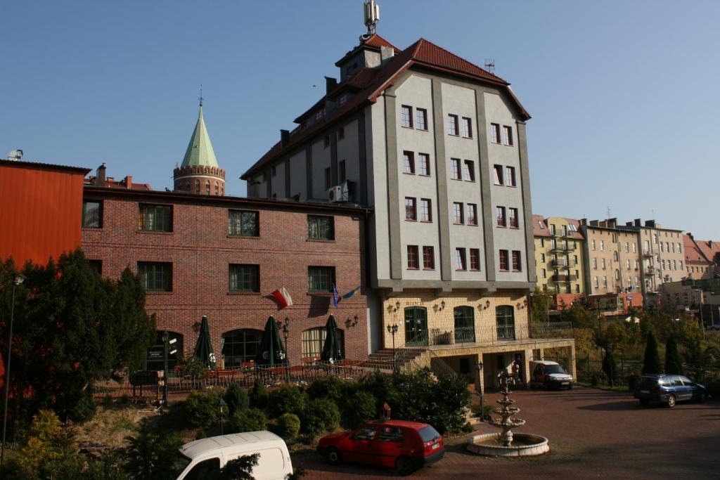 a large building with a clock on the front of it at Hotel Spichlerz in Stargard