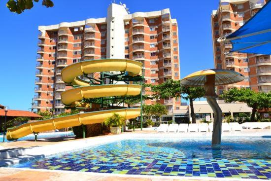 a pool with a water slide in front of a building at Apartamento Império Romano in Caldas Novas