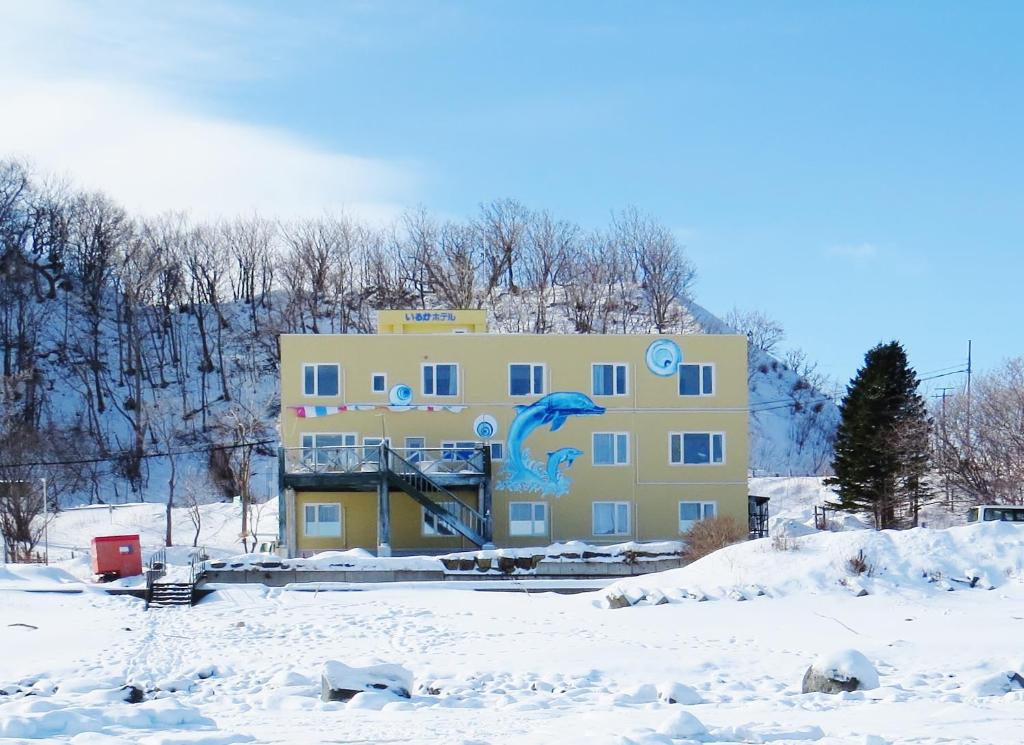 a yellow building with a painting on it in the snow at Iruka Hotel in Shari