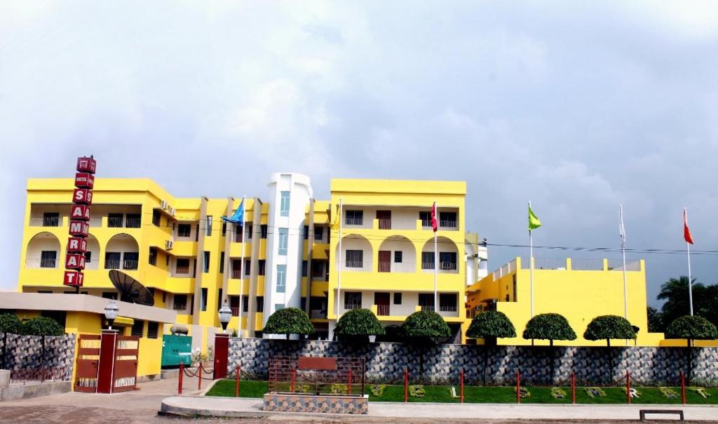 a yellow building with flags in front of it at Hotel Samrat in Baharampur