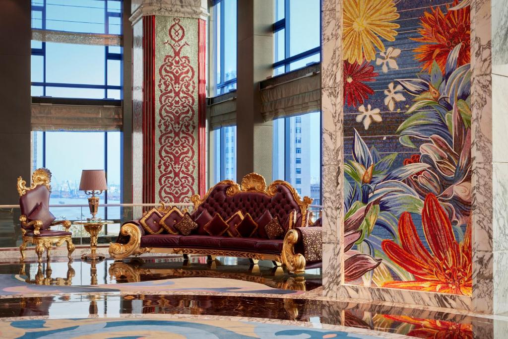 a living room with a couch and a wall of windows at The Reverie Saigon in Ho Chi Minh City