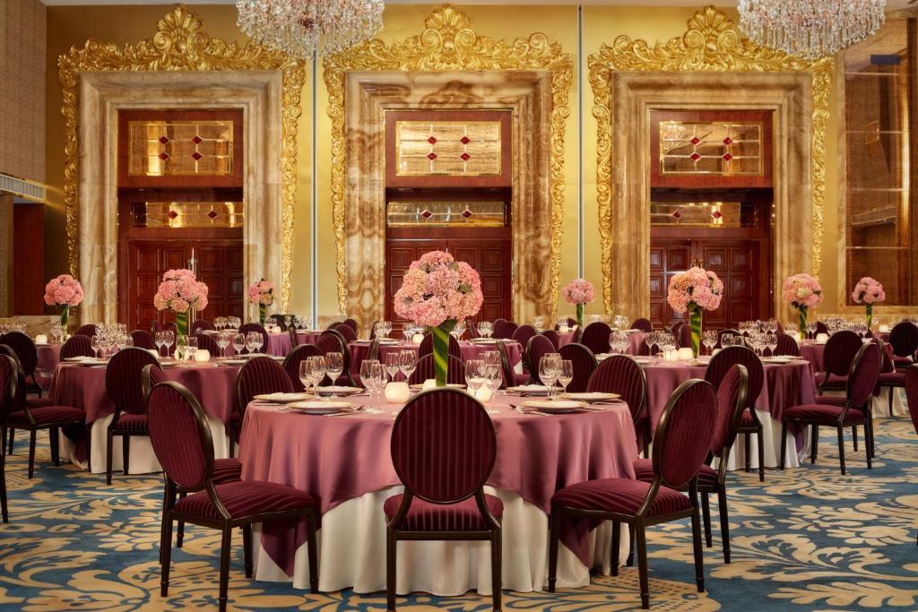 a banquet room with tables and chairs and pink flowers at The Reverie Saigon in Ho Chi Minh City