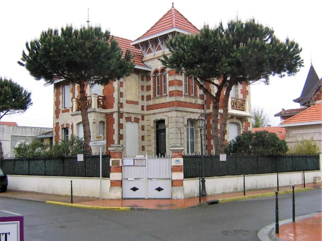 a large building with two trees in front of it at Villa Le Cid in Soulac-sur-Mer