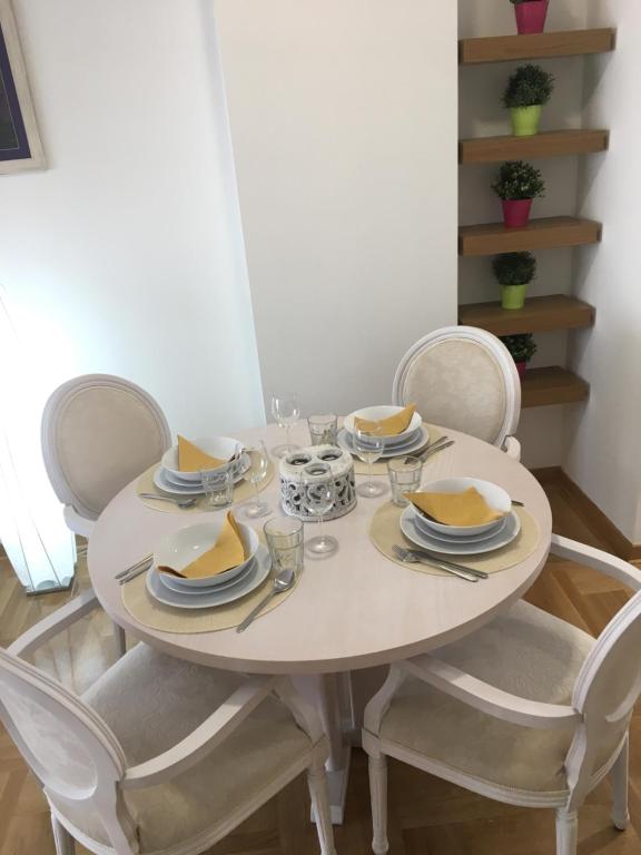 - une table à manger blanche avec des chaises, des assiettes et des bols dans l'établissement Apartment Posejdon, à Belgrade