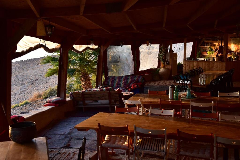 un restaurant avec des tables et des chaises en bois dans un champ dans l'établissement Zman Midbar Eco Spirit Lodge for Peace, à Arad