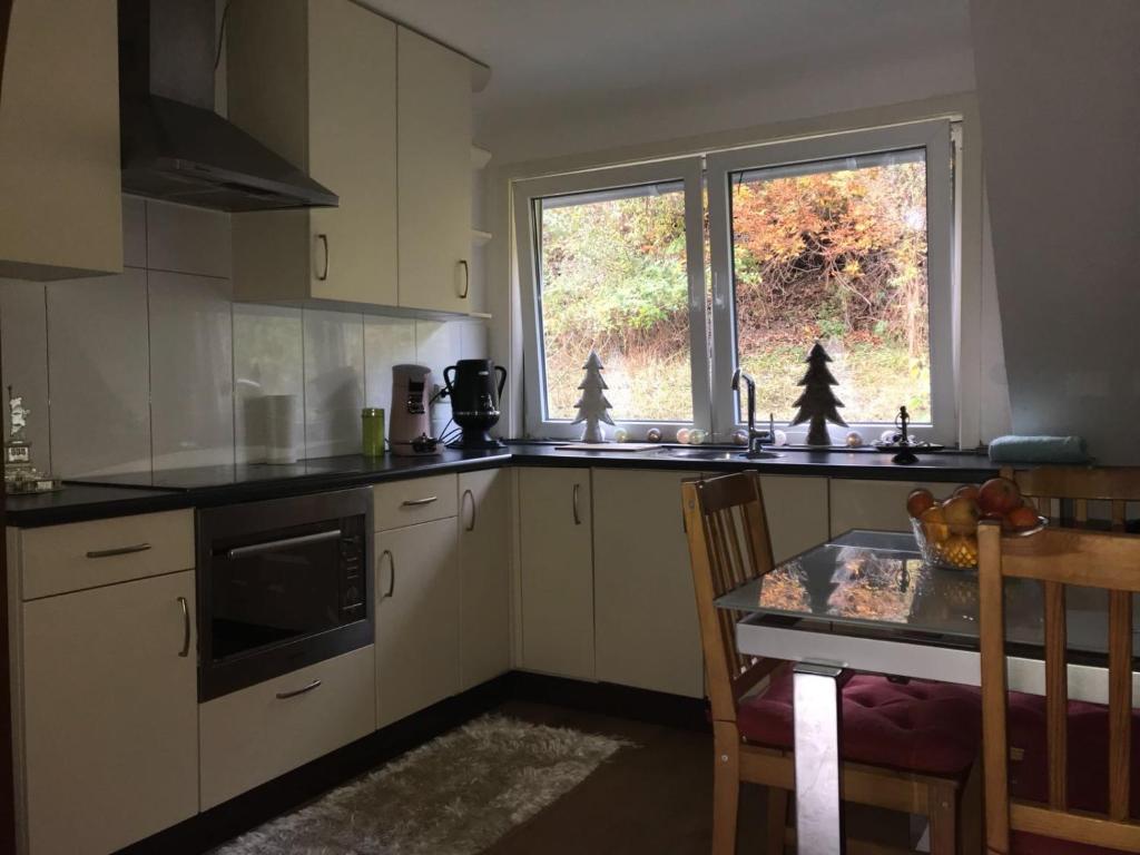 cocina con armarios blancos, mesa y ventana en Winterbergappartments en Winterberg