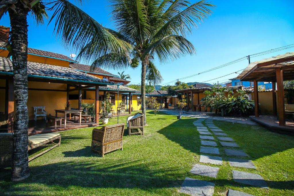 a resort yard with chairs and palm trees at Pousada das Pedras in Paraty