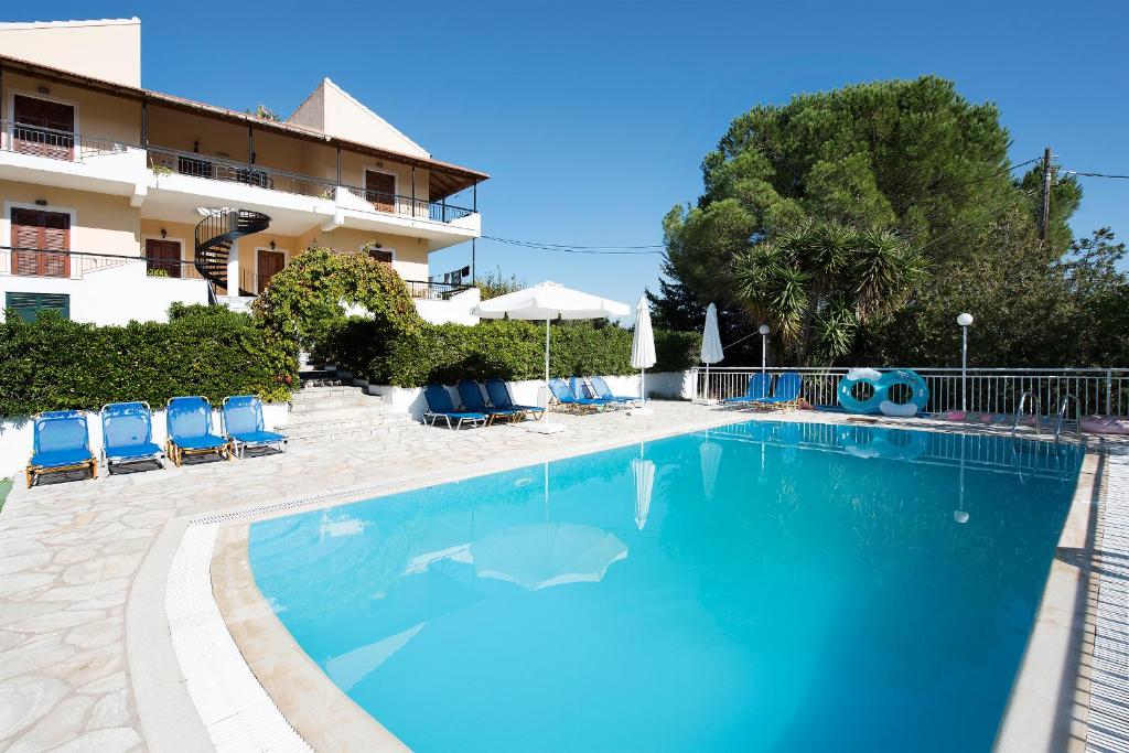 een groot zwembad met blauwe stoelen en een gebouw bij Cochelli Villas in Kassiopi