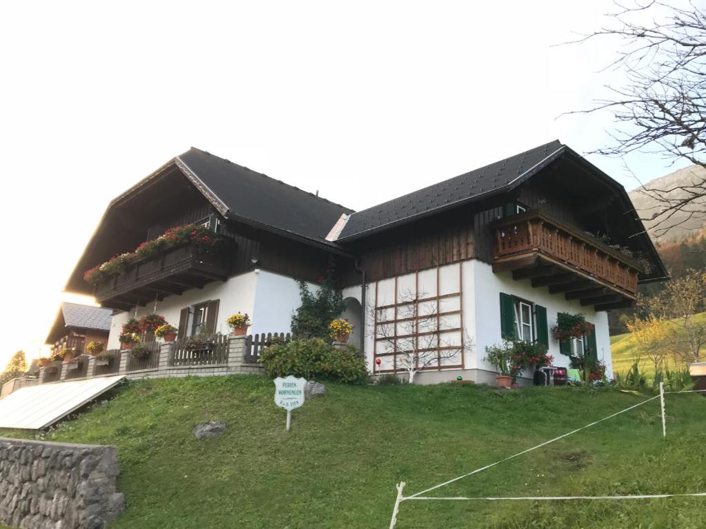 una casa blanca con techo negro y patio en Ferienwohnung Syen, en Grundlsee