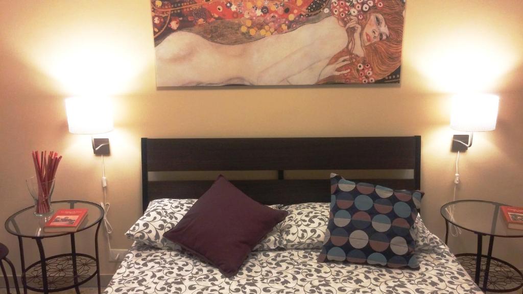 een slaapkamer met een bed met 2 tafels en een schilderij bij Casa Giramondo in Rome