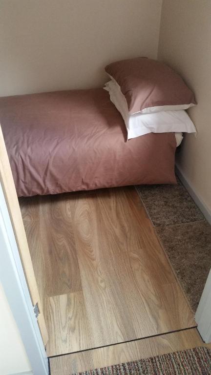 a bed in a small room with a wooden floor at Stone Eater in Marsden