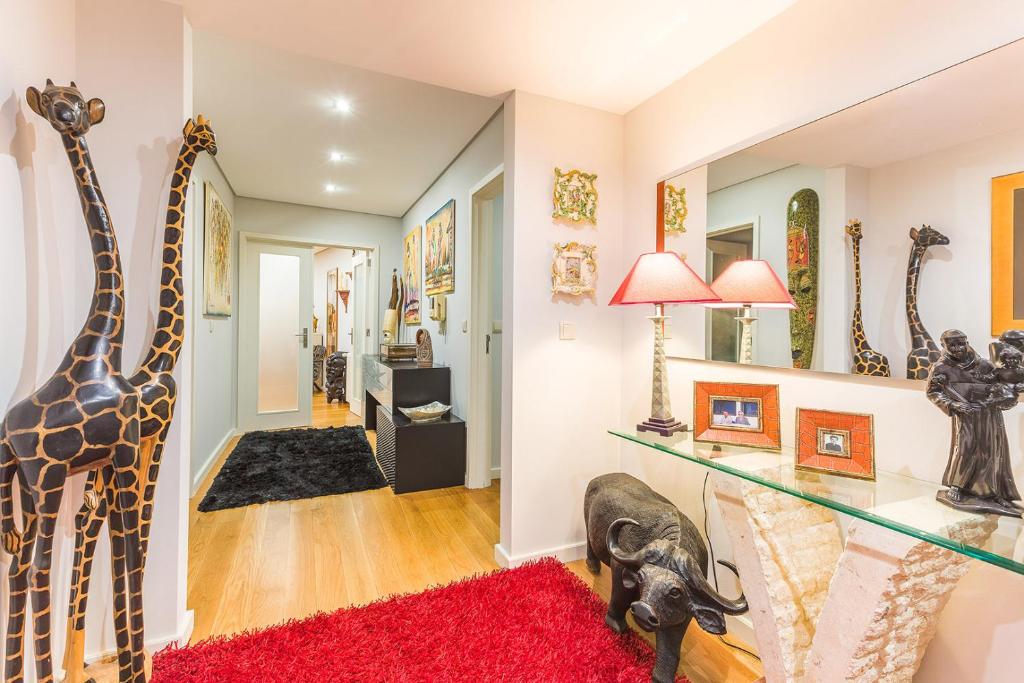 a room with giraffe statues and a red rug at Sunset in São Félix da Marinha