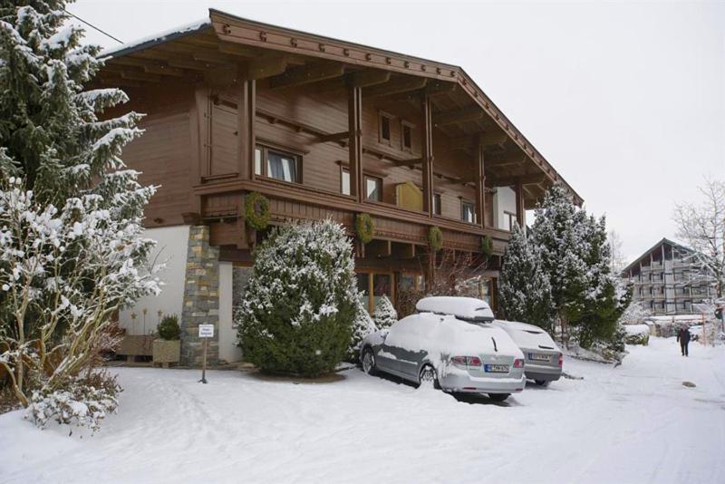 deux voitures garées devant une maison dans la neige dans l'établissement Haus Friederike - "Apartment KaiserTor", à Ellmau