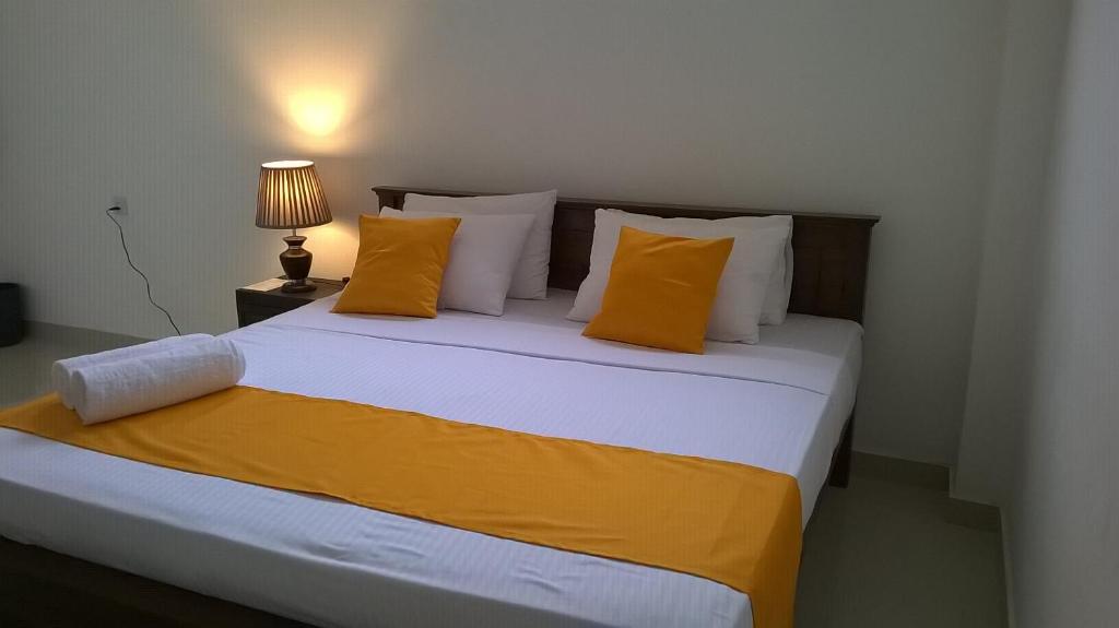 a bedroom with a large bed with orange and white pillows at Kandy Citylights Residence in Kandy