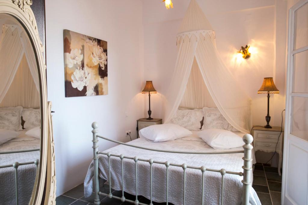 a bedroom with a bed with a canopy and a mirror at Akrogiali Pension in Platis Gialos