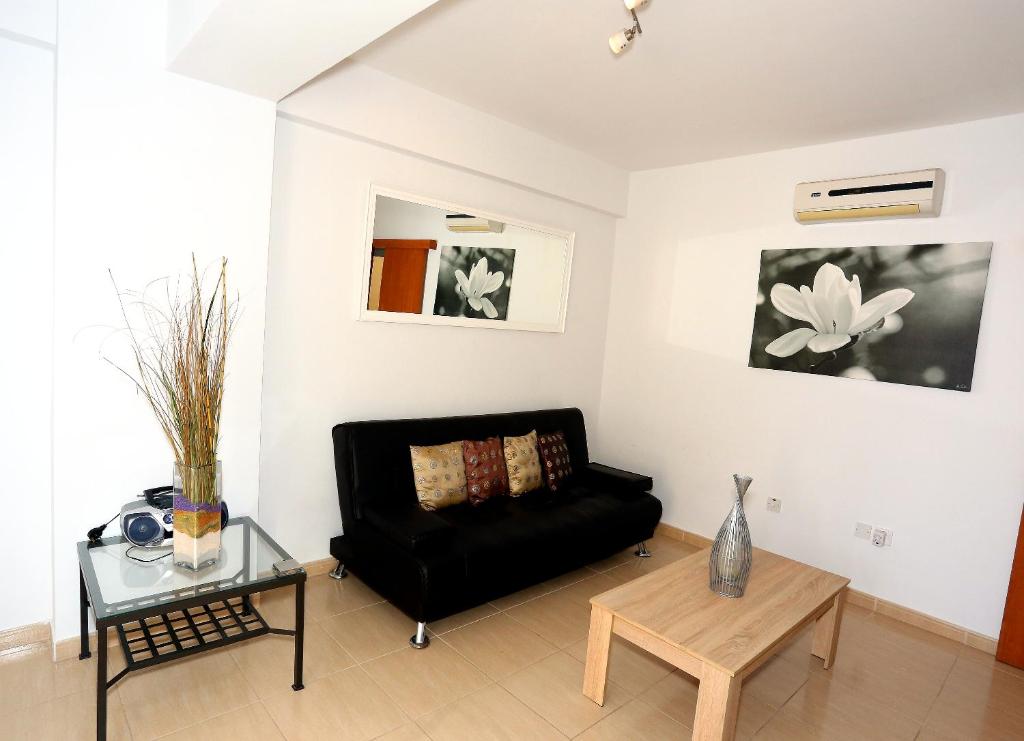 ein Wohnzimmer mit einem schwarzen Sofa und einem Tisch in der Unterkunft Penelope Court Apartment 102 in Larnaka