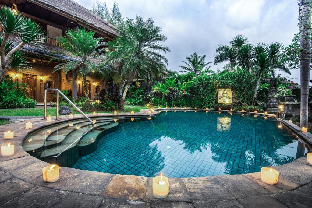 a swimming pool in front of a house with palm trees at Hotel Bunga Permai in Ubud