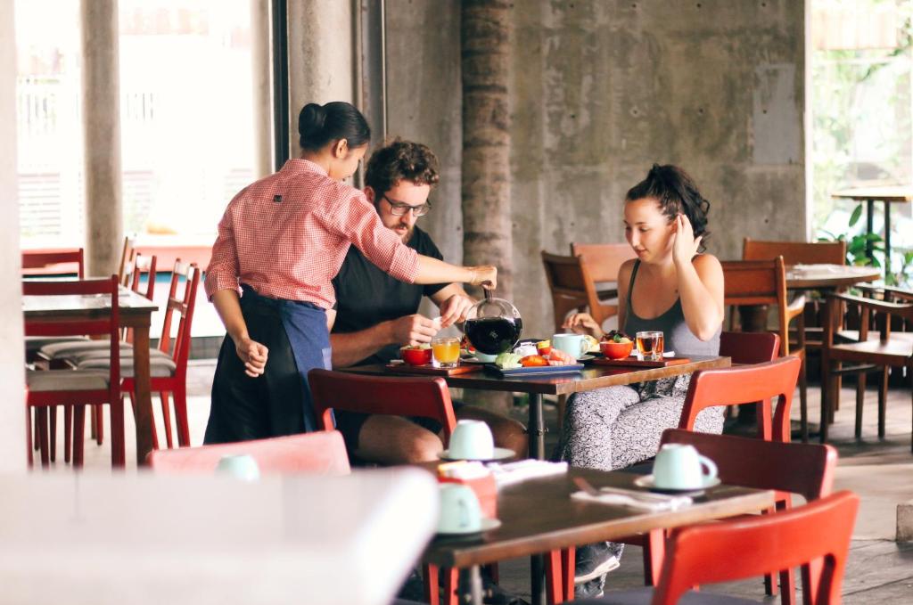a group of people standing around a table in a restaurant at Grandmas Plus Hotel Seminyak in Seminyak