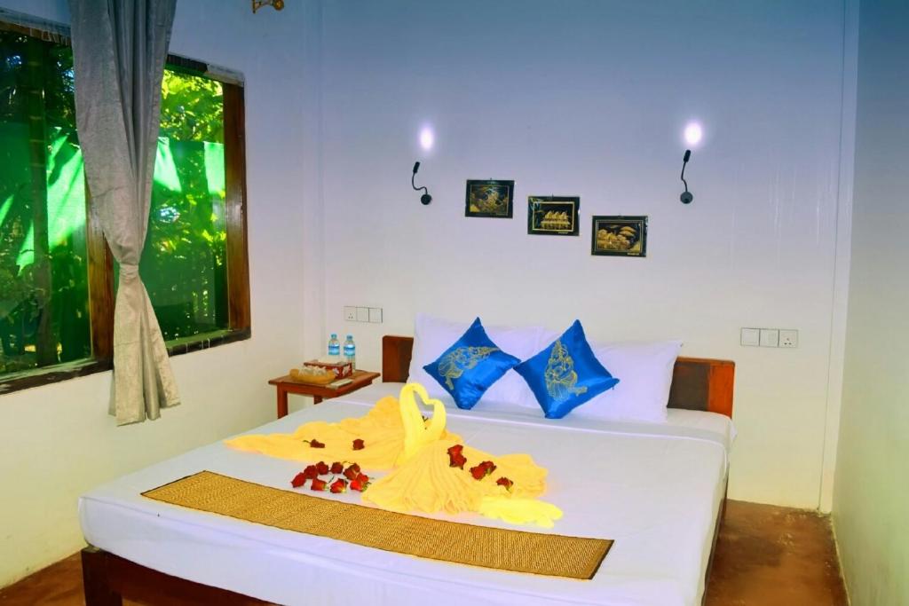 a bedroom with a white bed with flowers on it at Mingalarpar Ngapali Guest House in Ngapali