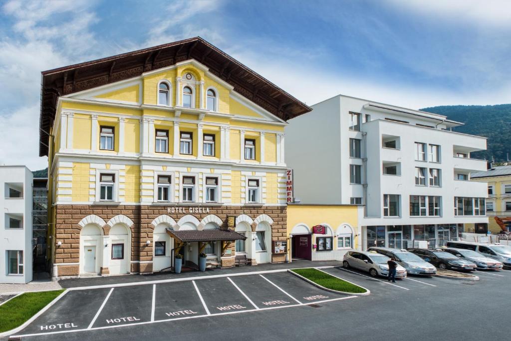 ein gelbes Gebäude auf einem Parkplatz neben Gebäuden in der Unterkunft Hotel Gisela in Kufstein