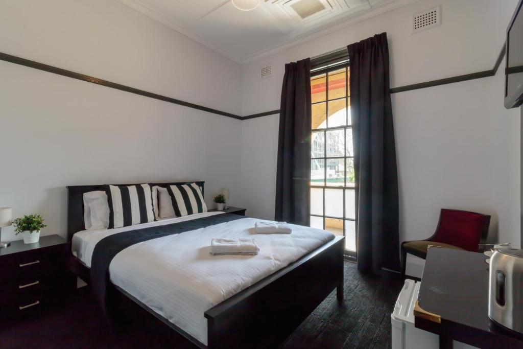 a bedroom with a large bed and a window at Royal Hotel Ryde in Sydney