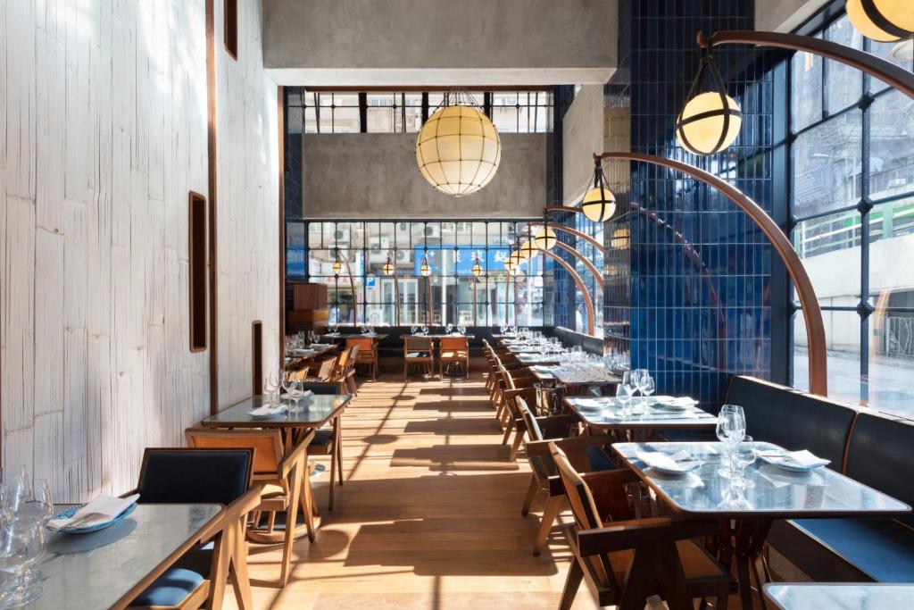 una sala da pranzo con tavoli, sedie e finestre di The Fleming Hong Kong a Hong Kong