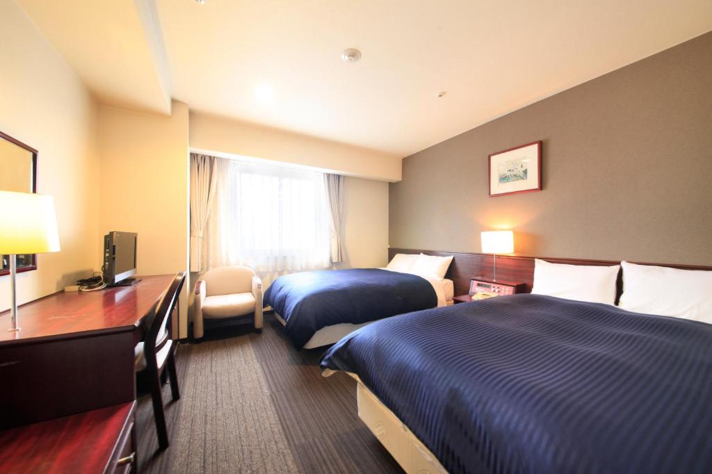 um quarto de hotel com duas camas e uma televisão em Quintessa Hotel Ogaki em Ogaki
