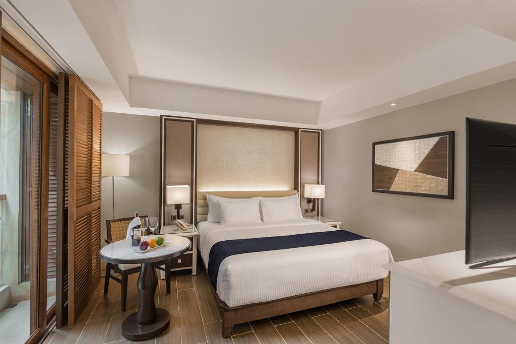 a hotel room with a bed and a table and a television at Henann Crystal Sands Resort in Boracay