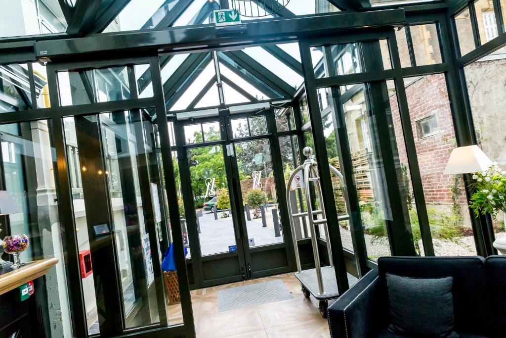 an open glass door to a building with a chair at Villa Augeval Hôtel de charme & Spa in Deauville