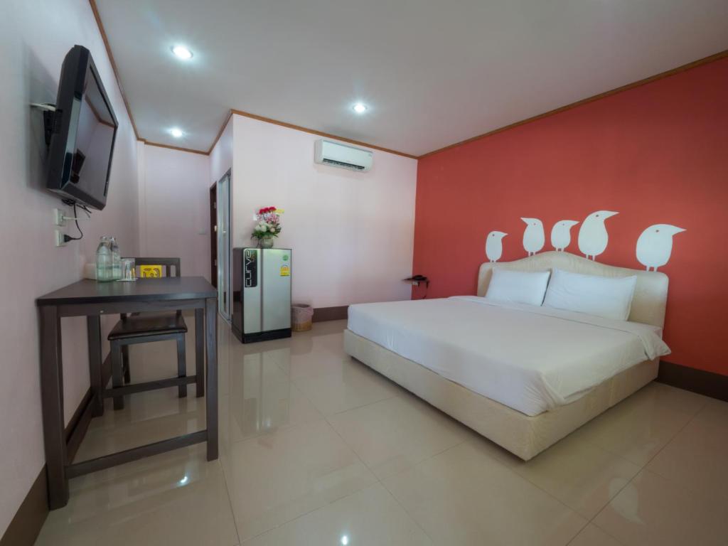 1 dormitorio con cama blanca y pared roja en A Nice Resort, en Buriram