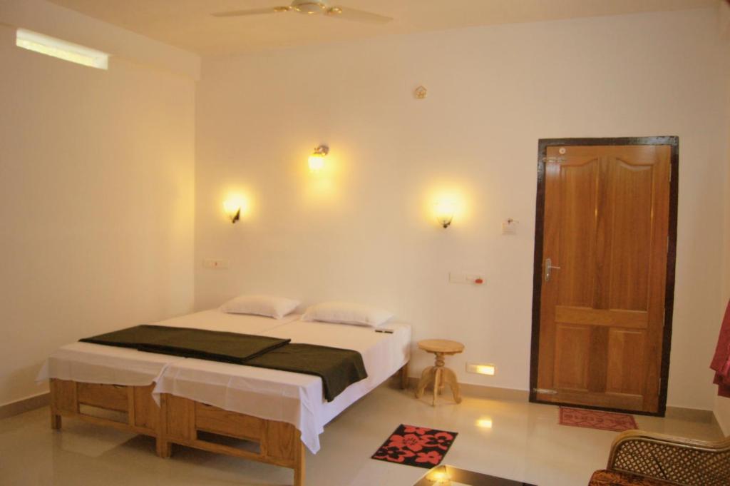 a bedroom with a bed and a wooden door at Blessdale Homestay in Thekkady