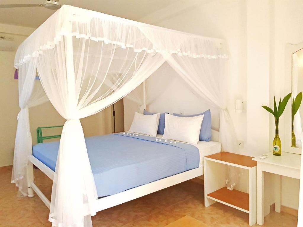 1 dormitorio con 1 cama azul con dosel en Neela's Beach Inn en Hikkaduwa