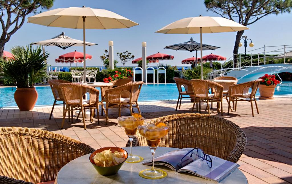 a table with wine glasses on it next to a pool at Ruhl Beach Hotel & Suites in Lido di Jesolo