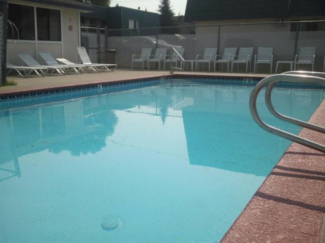 a large blue swimming pool with chairs and chairs at Apple Tree Inn in Spokane