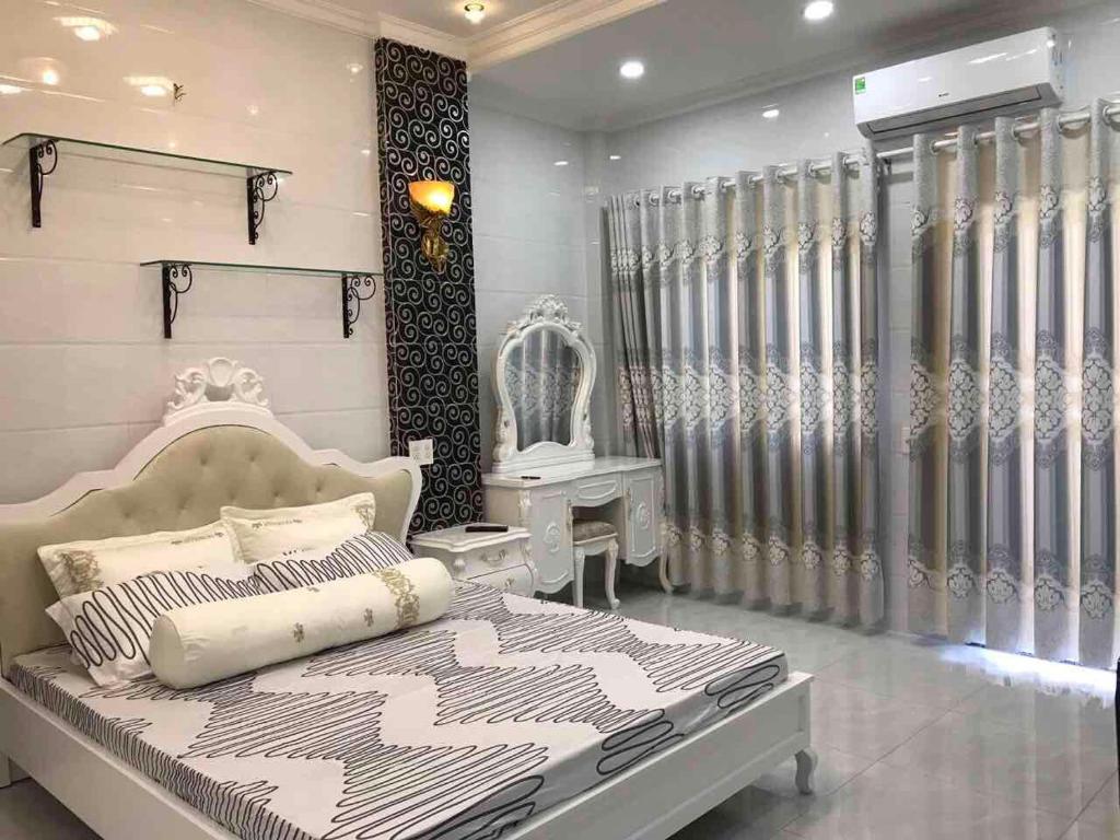 ein Schlafzimmer mit einem Bett in einem Zimmer mit Vorhängen in der Unterkunft The Moana House in Ho-Chi-Minh-Stadt