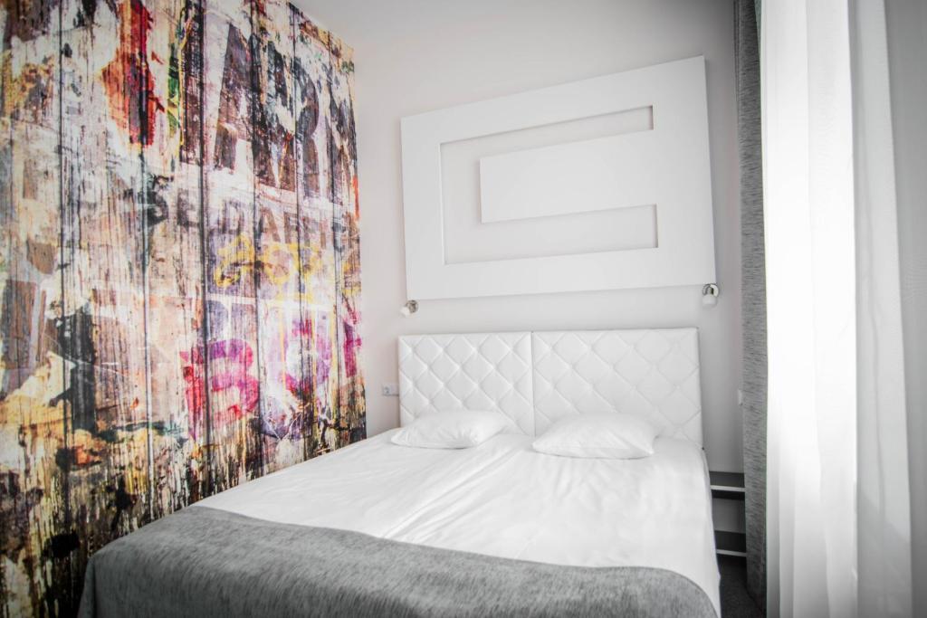 a bedroom with a white bed with a colorful wall at HomeLike Hotel in Daugavpils