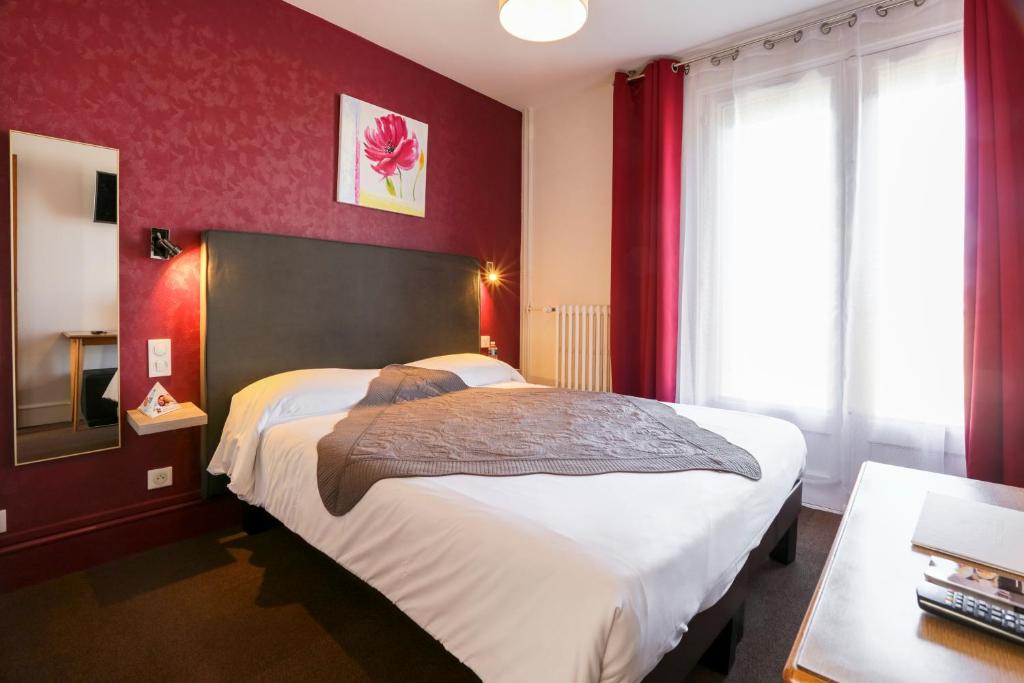アングレームにあるBrit Hotel Terminusの赤い壁のベッドルーム1室(大型ベッド1台付)
