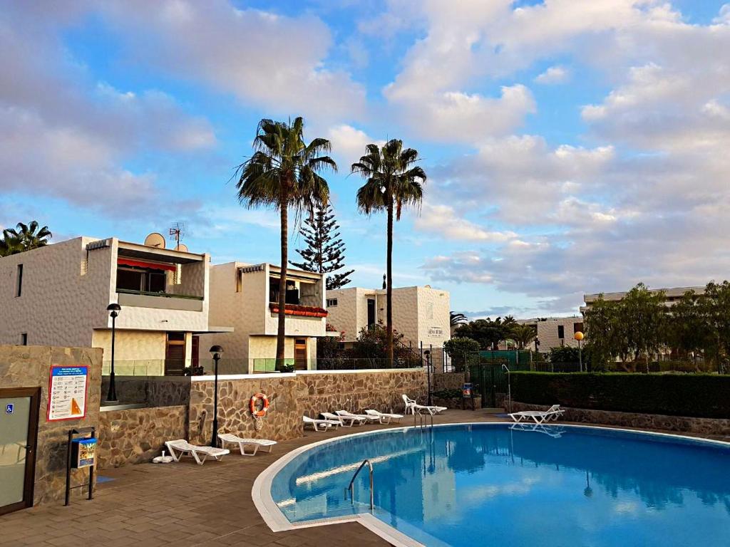 une grande piscine avec des chaises et des palmiers dans l'établissement Lovely Apartment close to the Beach Apartamerica LA140, à Playa de las Americas