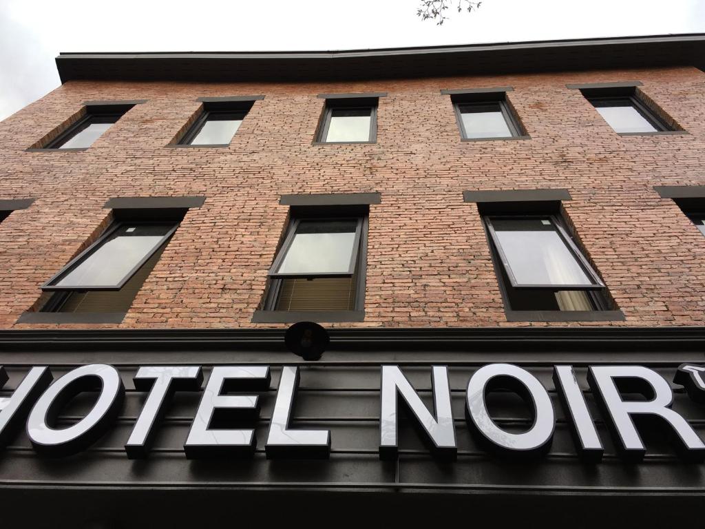 a sign for a hotel north on a brick building at Hotel Noir in Chiang Mai