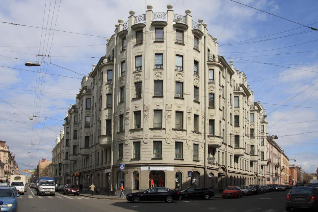 un grand bâtiment blanc dans une rue de la ville avec des voitures dans l'établissement Aximaris furnished rooms, à Saint-Pétersbourg