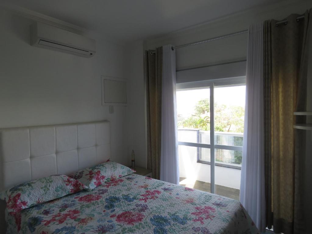 Schlafzimmer mit einem Bett und einem Fenster mit Aussicht in der Unterkunft Apartamento na Praia dos Ingleses in Florianópolis