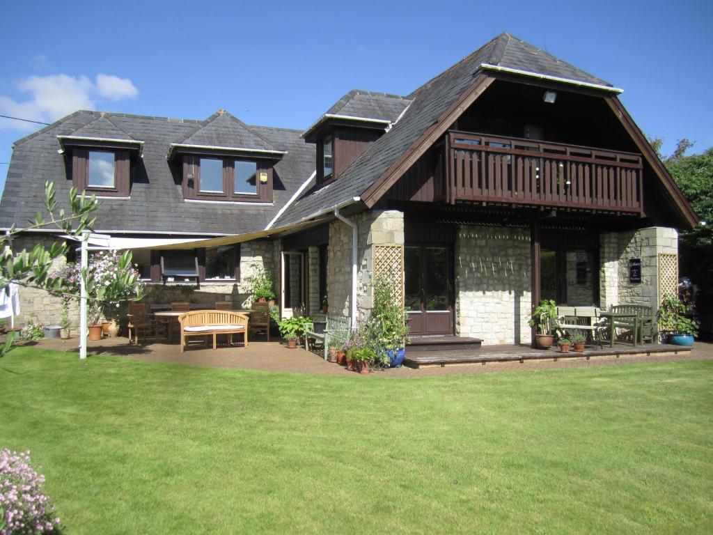 a house with a deck and a lawn at Hare Lodge B&B in Tisbury