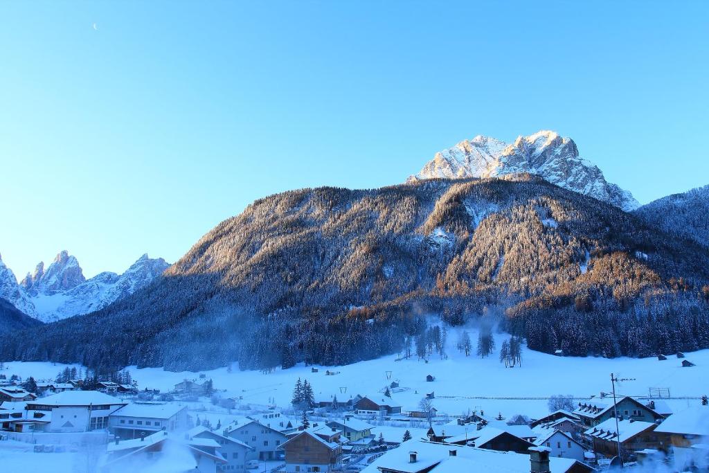 Une montagne au loin avec un village dans la neige dans l'établissement Hotel Willy, à Sesto