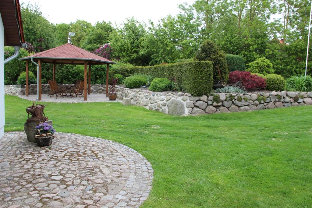 un jardín con una pared de piedra y un cenador en Ferienhaus-Grambzow, en Grambzow