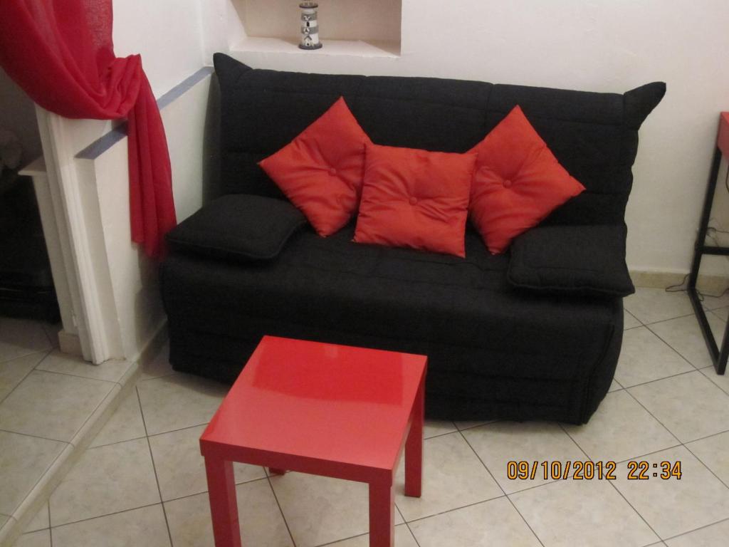 マントンにあるStudio Vieux Mentonの赤い枕2つと赤いテーブル付きの黒いソファ