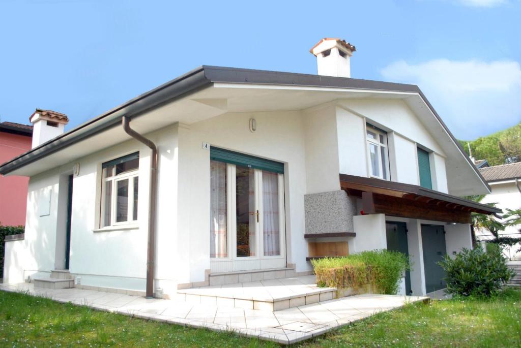 una casa bianca con una porta blu di Villetta Vela a Lignano Sabbiadoro