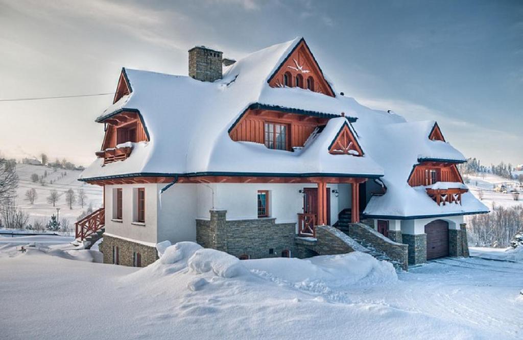 une maison recouverte de neige dans l'établissement Willa Grandeus, à Bukowina Tatrzańska