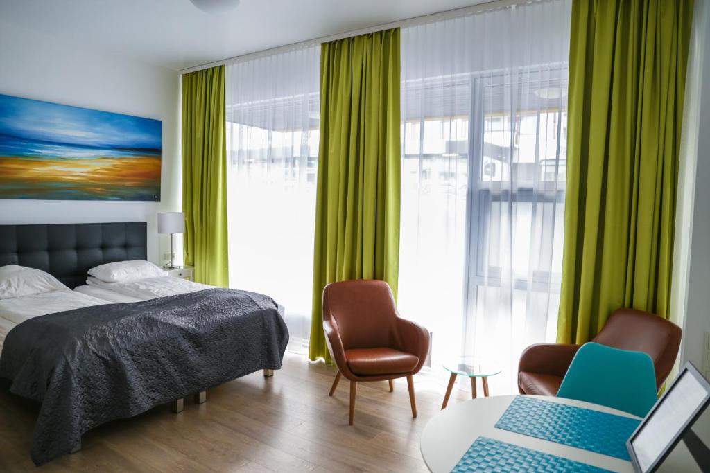 Iceland Comfort Apartments by Heimaleiga في ريكيافيك: غرفة نوم مع ستائر خضراء وسرير وكرسيين