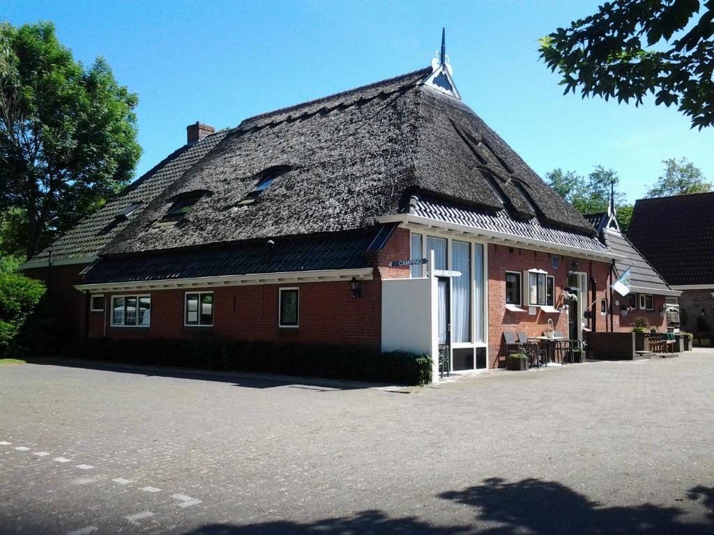 een groot gebouw van rode baksteen met een dak bij Bed & Breakfast Meinsma in Moddergat