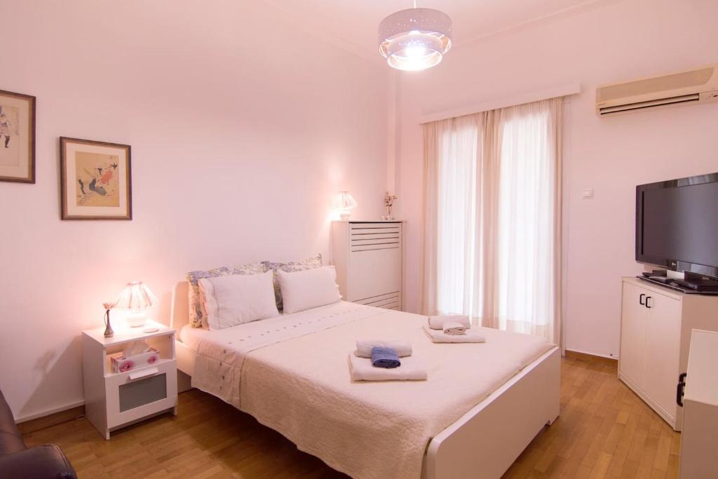 アテネにあるAreos Apartmentの白いベッドルーム(ベッド1台、薄型テレビ付)